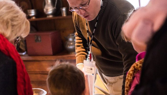 Man talking with family at the Living History lab at the House of the Seven Gables.
