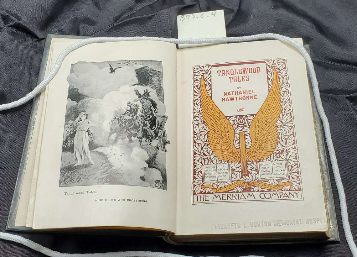A metal book cover with torch and floral design. Contains the text: Tanglewood Tales Nathan'l Hawthorne|A metal book cover with wreath and sconce design.|Two book pages