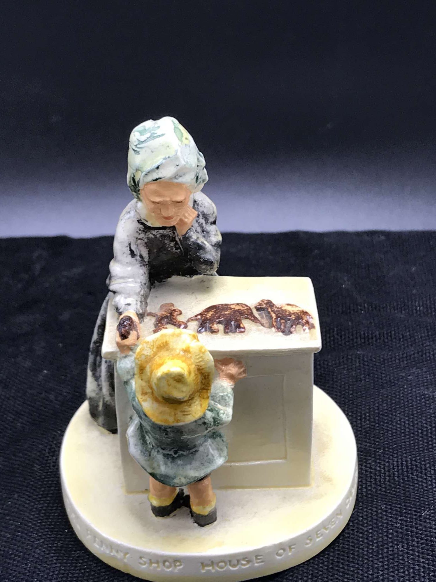 four small ceramic figurines arranged in a circle: a man at a desk