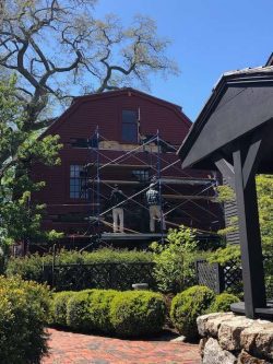 Preservation carpenter Brian Payne (left) and Preservation Director Paul Wright (right) on scaffolding at the right side of the Nathaniel Hawthorne Birthplace making repairs to a beam where rot was found in May 2022.