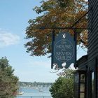 The house of Seven Gables sign with a view of the ocean on a sunny day.