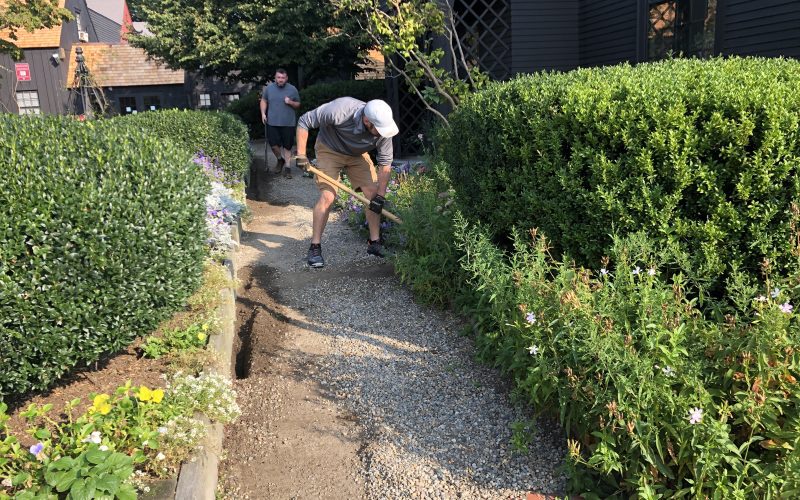 A man works on bushes in the seaside garden.