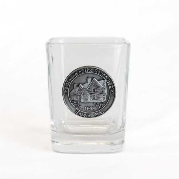 The front of the Square House of the Seven Gables Shot Glass. It is a glass shot glass with a pewter medallion of the House of the Seven Gables.