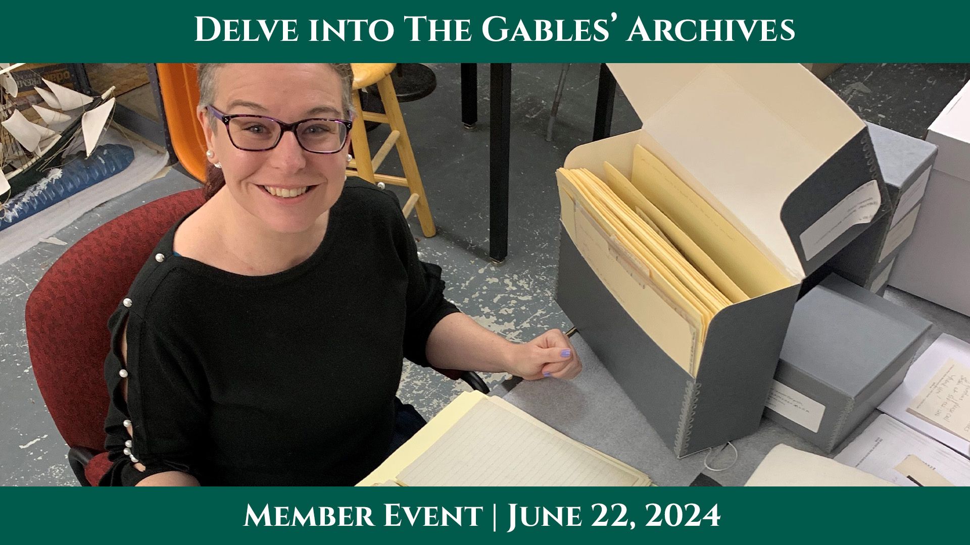 A white woman smiling at the camera, seated at a desk with file folders and documents.